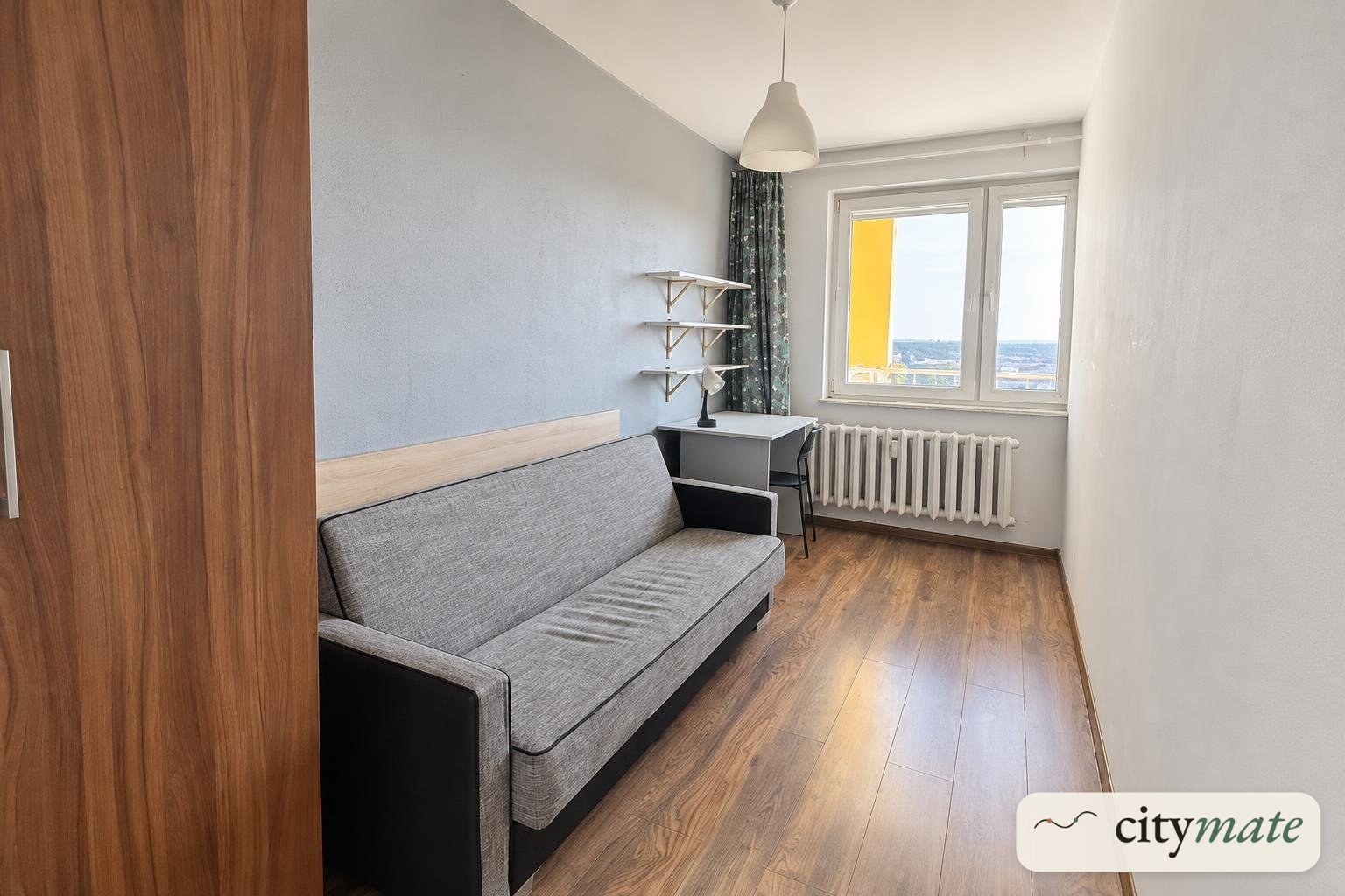 Room with a sofa and a desk by a large window